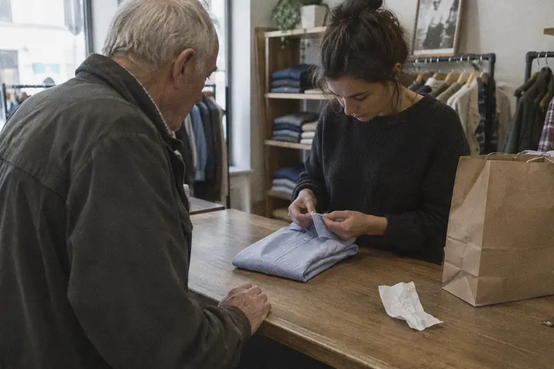 Una dependienta revisa la costura de una camisa que un cliente ha traído para cambiar