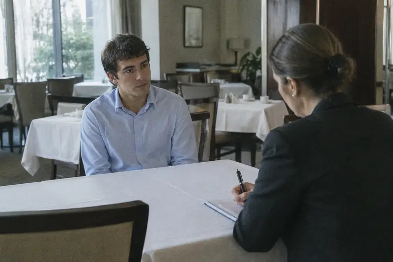 Un joven hace una entrevista de trabajo con la encargada de un hotel en el comedor vacío