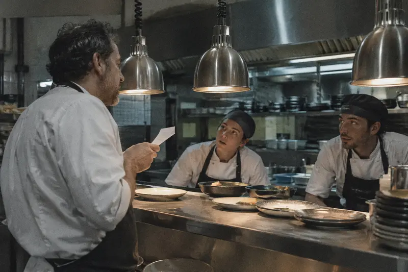 Un jefe de cocina canta una comanda en el pase y los cocineros de la línea le contestan