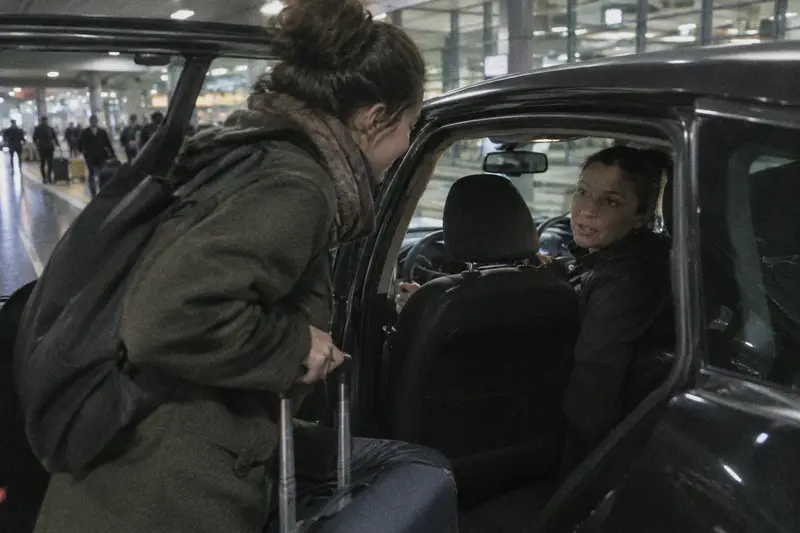 Una conductora se gira para hablar con la pasajera que acaba de subir al coche en la zona de llegadas