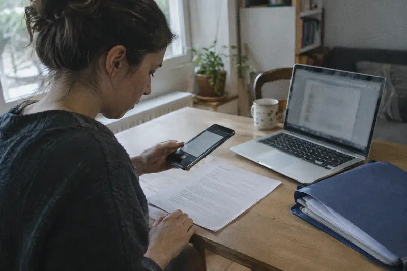 Una mujer escanea un documento con el móvil sobre la mesa para presentarlo por internet