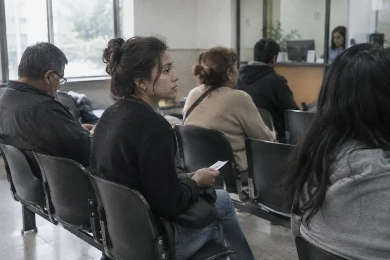 Una mujer espera su turno con el número en la mano en la sala de una oficina pública